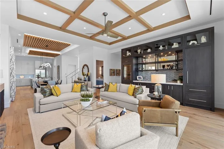 Living room with bar area, coffered ceiling, light wood-style floors, a ceiling fan, and recessed lighting