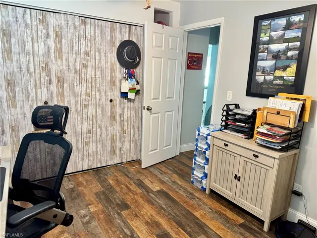 Office area with dark wood-style flooring and baseboards