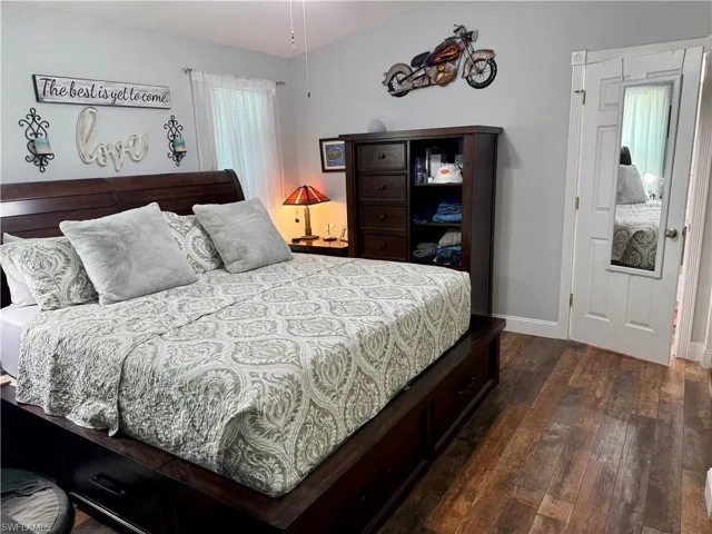 Bedroom with dark wood-style floors and baseboards
