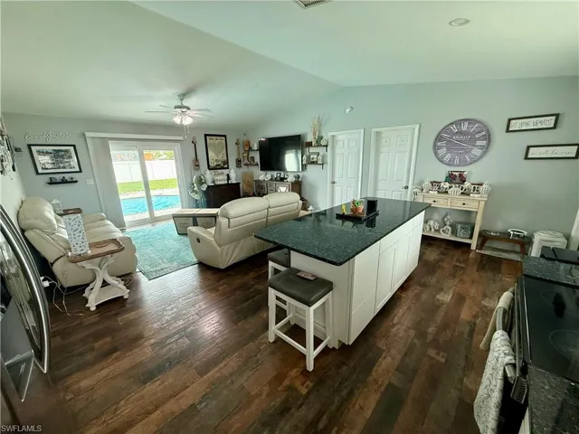 Kitchen with black range with electric stovetop, lofted ceiling, dark countertops, ceiling fan, and dark wood-type flooring