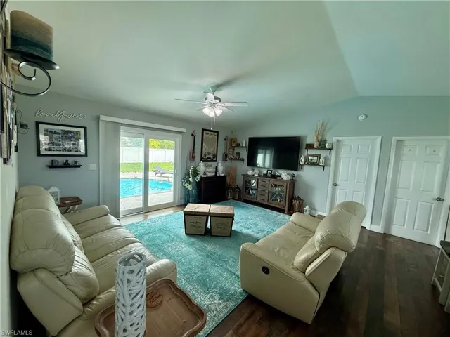 Living room with ceiling fan, wood finished floors, and vaulted ceiling