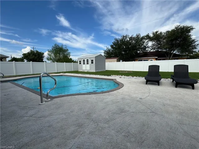 View of pool with a patio area, a fenced backyard, and a shed