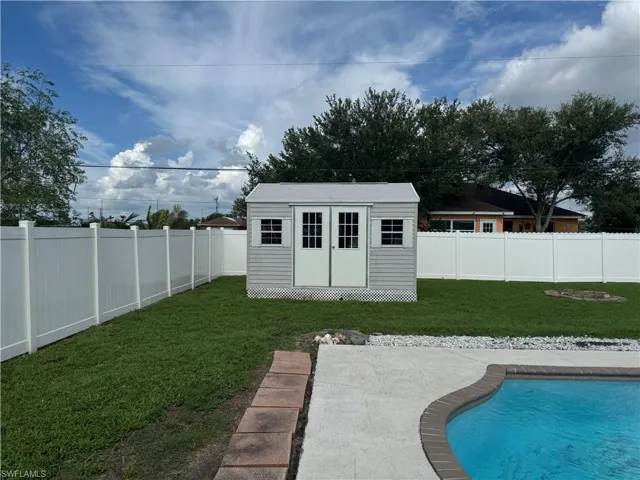 View of pool with a fenced backyard and a shed