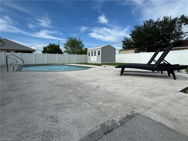 View of pool featuring a patio, a fenced backyard, and a shed