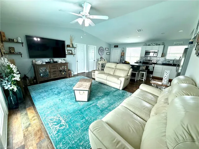 Living area with dark wood finished floors, lofted ceiling, and ceiling fan