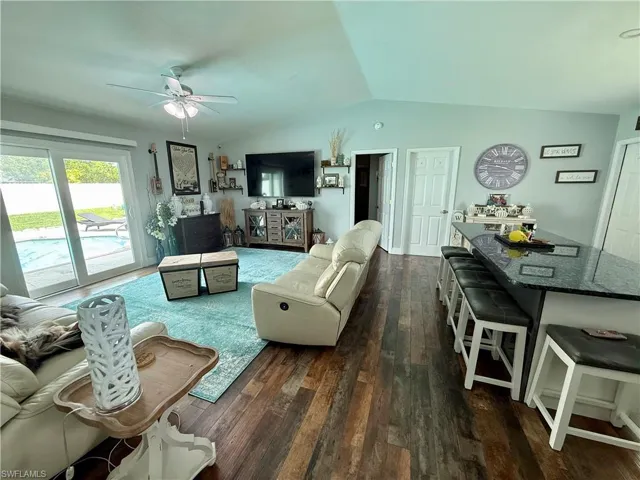Living room with a ceiling fan, dark wood finished floors, and vaulted ceiling