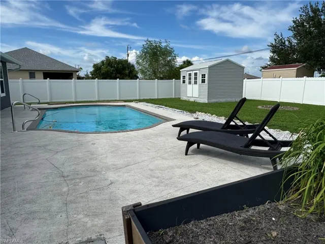 View of swimming pool with a patio, a fenced backyard, and a storage unit