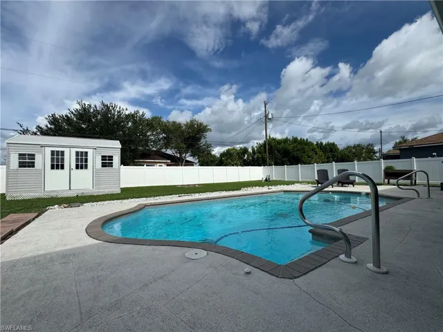 View of swimming pool with a patio, an outdoor structure, and a fenced backyard