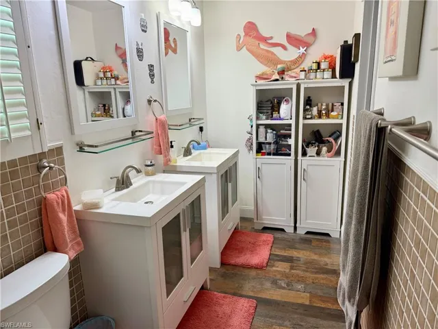 Bathroom featuring tile walls, wood finished floors, and vanity