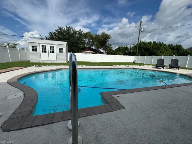 View of pool featuring a fenced backyard, an outbuilding, and a patio area