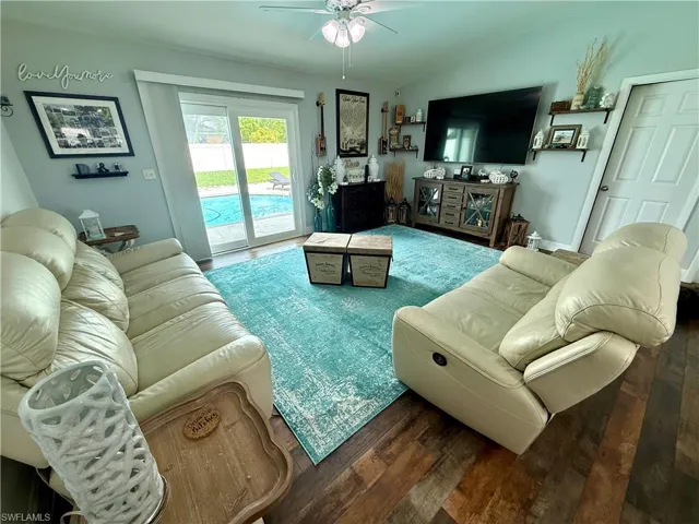 Living room with wood finished floors, a ceiling fan, and lofted ceiling