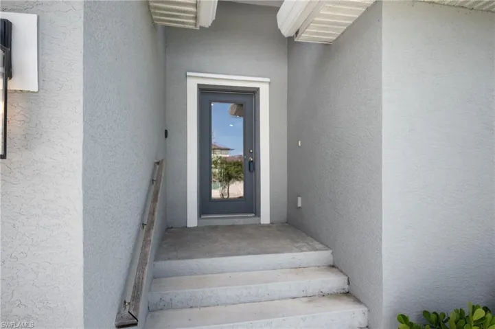 Entryway featuring concrete steps, stucco exterior, and a glass-paneled door