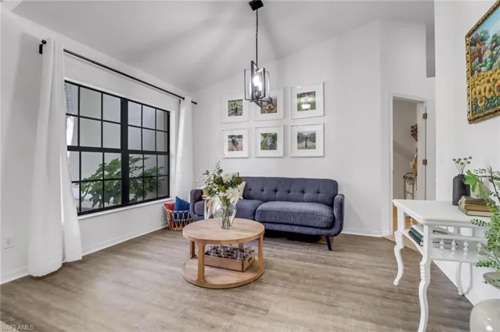 Sitting room with hardwood / wood-style floors, vaulted ceiling, and an inviting chandelier