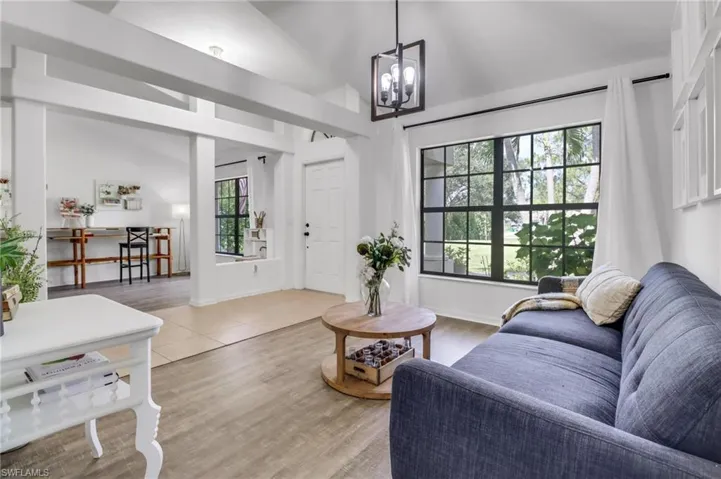 Living room featuring hardwood / wood-style flooring, a chandelier, high vaulted ceiling, and a healthy amount of sunlight