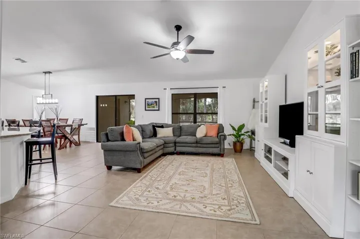 Tiled living room featuring ceiling fan with notable chandelier