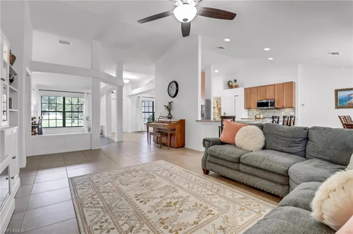 Tiled living room featuring high vaulted ceiling and ceiling fan