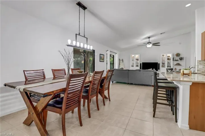 Dining room with lofted ceiling, ceiling fan, sink, and light tile patterned floors