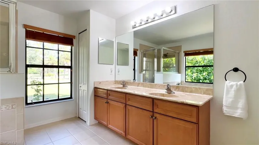 Bathroom featuring tile patterned floors, a wealth of natural light, a shower with door, and vanity