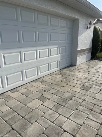 Garage door with panel detailing and a paver driveway