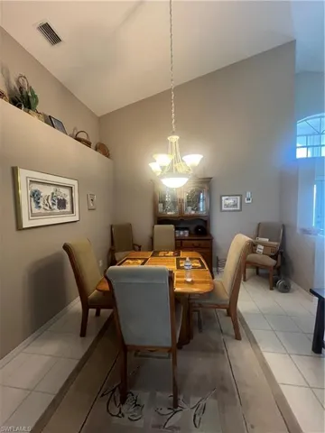 Vaulted ceiling interior with a decorative chandelier, elevated wall ledge, and tile flooring
