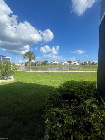Expansive green space featuring a large body of water, lush landscaping, and a distant palm tree