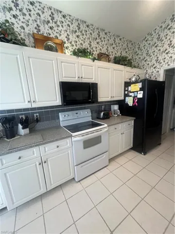 Kitchen featuring white cabinetry, gray countertops, a built-in microwave, white electric range, and tile flooring