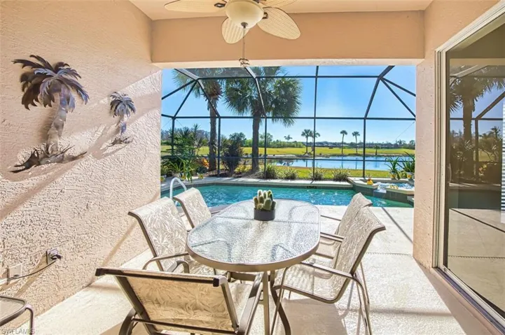View of patio / terrace featuring a sunroom, a ceiling fan, a lanai, a water view, and a pool with connected hot tub