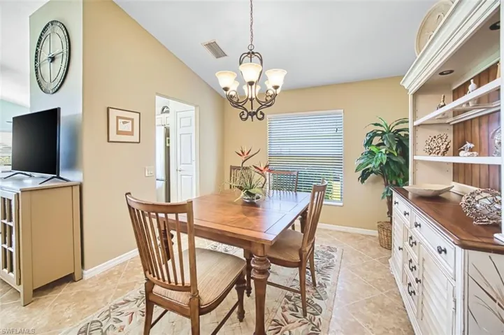 Dining room with vaulted ceiling, light tile patterned floors, and hanging lights