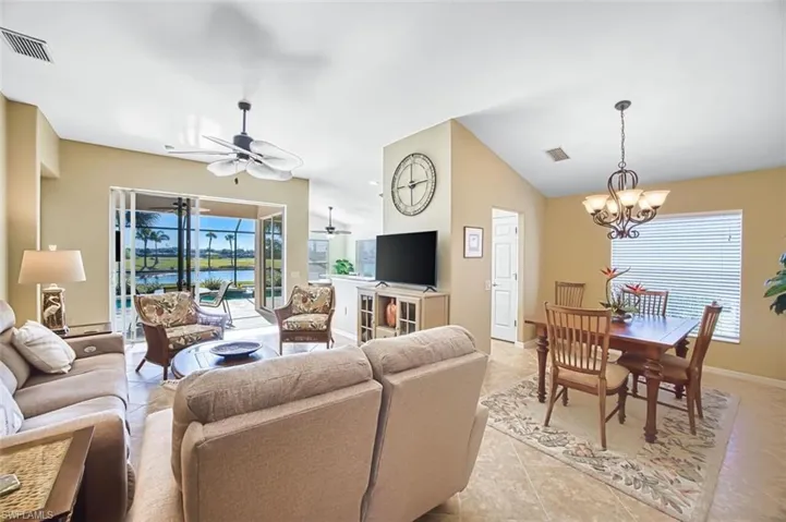 Living area with a ceiling fan, vaulted ceiling, hanging lights, and light tile patterned floors