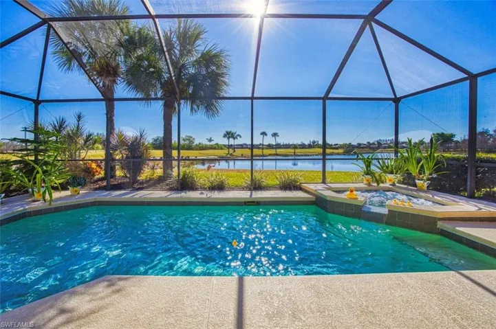 Integrated pool / hot tub with glass enclosure, a sunroom, and a water view