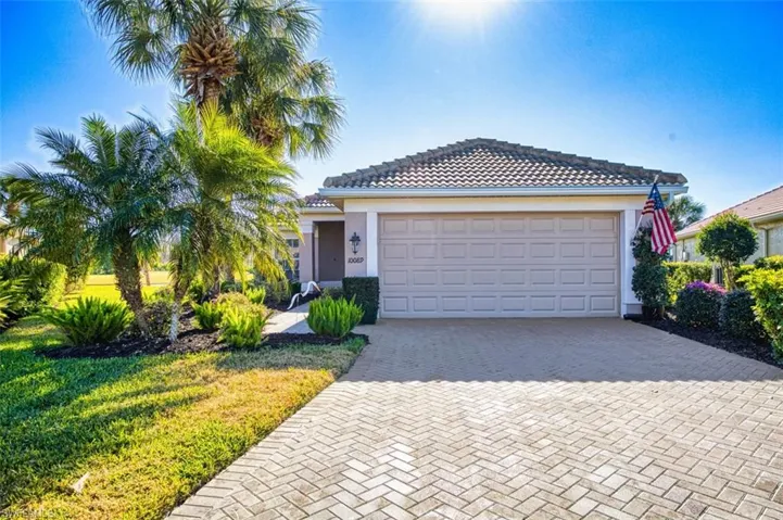 Ranch-style house featuring decorative driveway, stucco siding, a front yard, an attached garage, and a tile roof