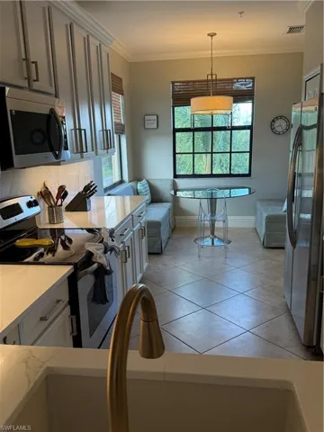 Kitchen featuring stainless steel stove, ornamental molding, fridge, plenty of natural light, and light tile patterned floors