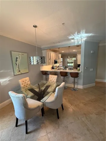 Dining area with crown molding, a textured ceiling, and light tile patterned floors