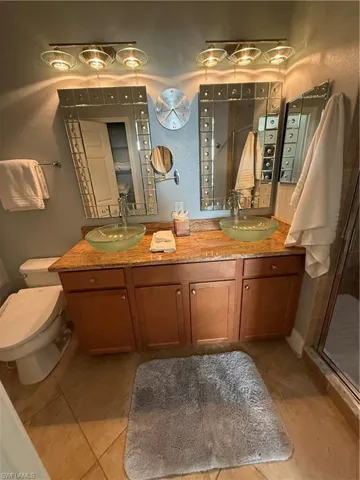 Full bathroom with double vanity, a stall shower, light tile patterned floors, and a textured wall