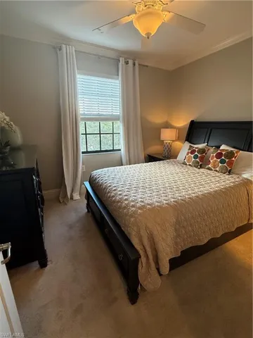 Bedroom featuring ornamental molding, light colored carpet, and a ceiling fan