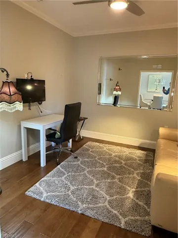 Office space featuring crown molding, dark wood-type flooring, and a ceiling fan