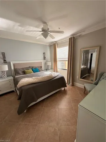 Bedroom featuring ornamental molding, a textured ceiling, a ceiling fan, and light tile patterned flooring