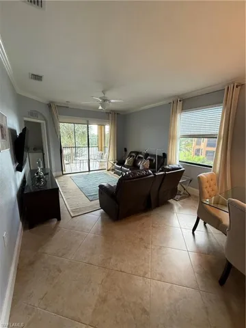 Living area featuring ornamental molding, a ceiling fan, and light tile patterned floors