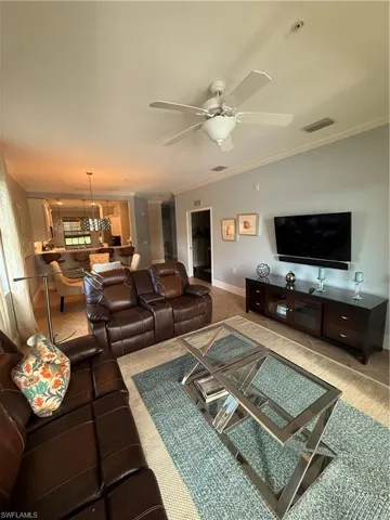 Living area featuring crown molding, ceiling fan, and carpet flooring