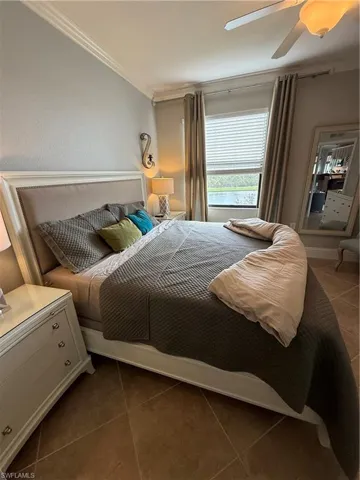 Bedroom featuring tile patterned floors, crown molding, and ceiling fan