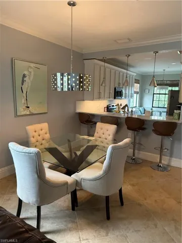 Dining space with crown molding and light tile patterned flooring