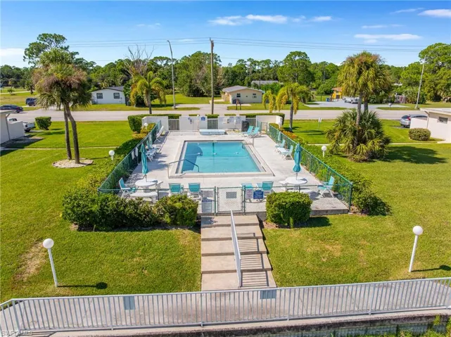 Community pool with a patio area, a gate, and view of wooded area