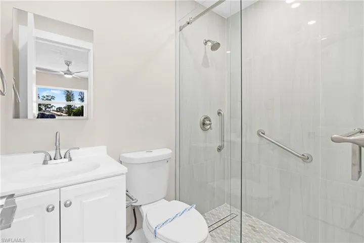 Bathroom featuring vanity, a stall shower, and ceiling fan