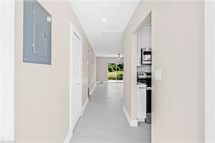 Corridor featuring electric panel, light tile patterned flooring, recessed lighting, and attic access