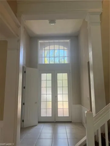 Doorway featuring a wainscoted wall, decorative columns, tile patterned flooring, a decorative wall, and french doors