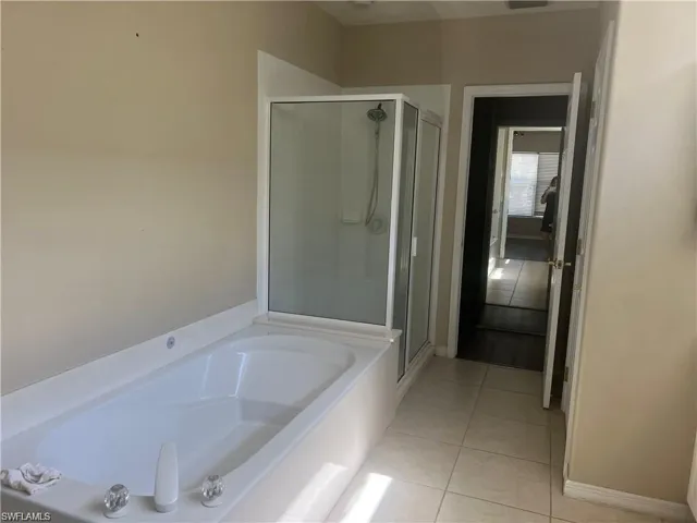 Bathroom with light tile patterned floors, a bath, and a stall shower