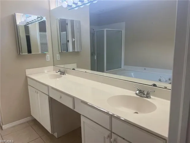 Bathroom featuring a garden tub, a stall shower, double vanity, and light tile patterned flooring