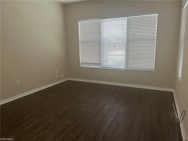 Spare room with baseboards and dark wood-style flooring