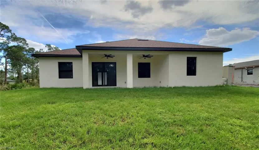 Rear view of property featuring a lawn and ceiling fan