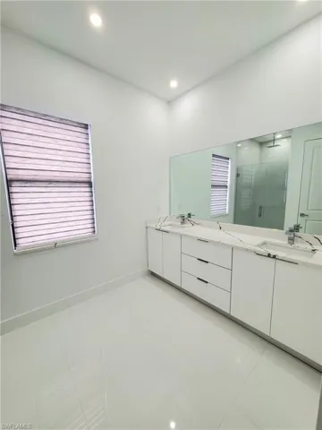 Bathroom featuring tile patterned flooring, vanity, and a shower with door